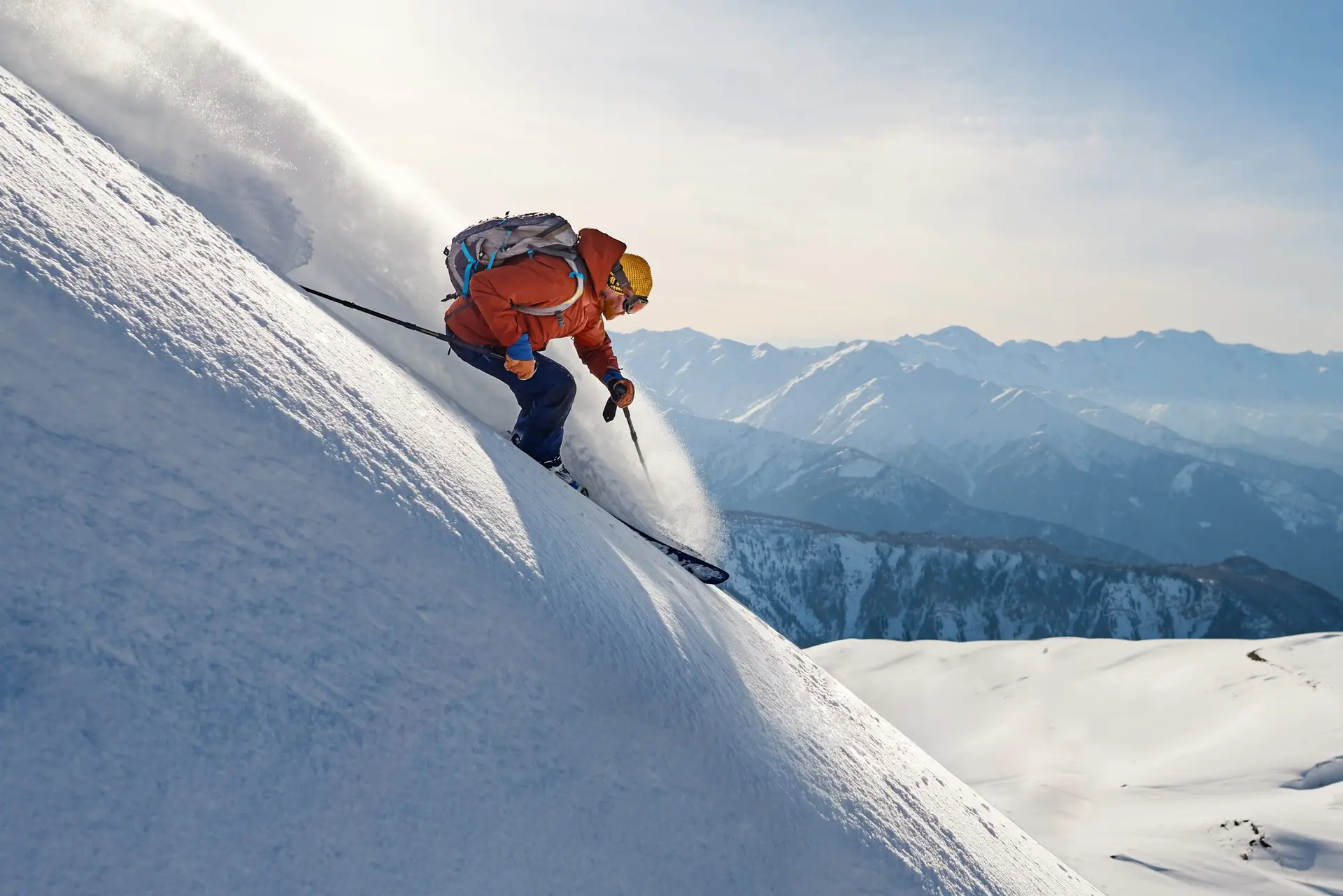 skier rides freeride on powder snow down the slope against the backdrop of the mountains