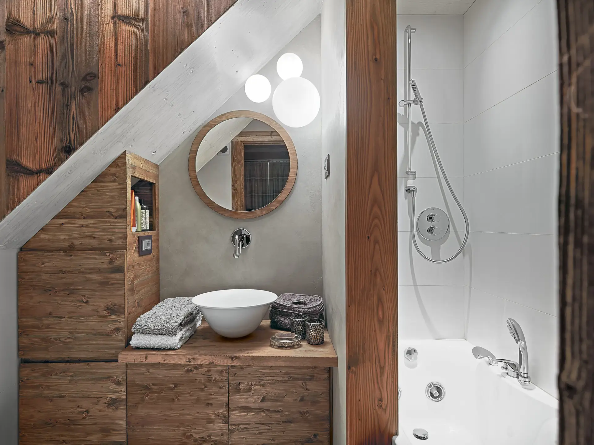 rustic bathroom interior, in the  foreground the counter top washbasin on the wooden washbasin  cabinet and the round mirror, on the right there is the  bathtub