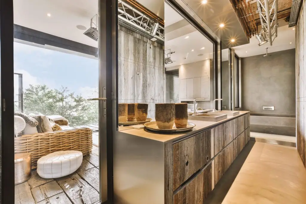 Contemporary minimalist style interior design of light studio apartment with wooden table and chairs in dining zone between open kitchen and living room with white walls and parquet floor