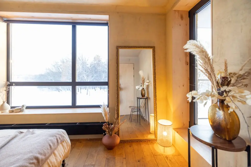 Stylish beige bedroom interior in natural boho style with big window and mirror during a morning sunshine