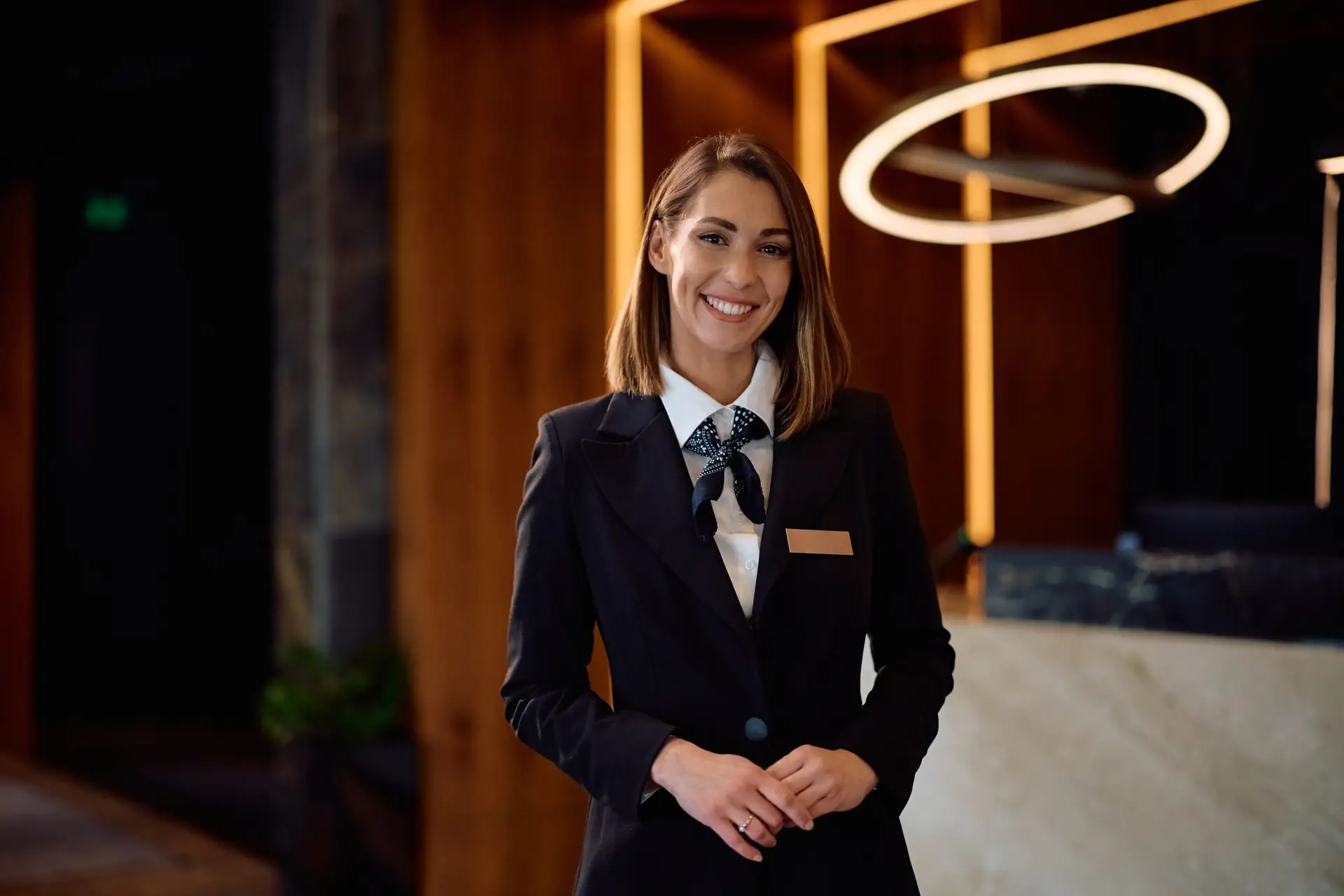Happy female concierge in hotel hallway looking at camera. Copy space.